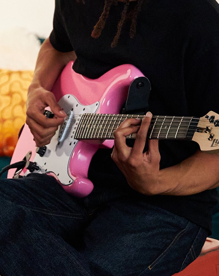 a person playing a pink electric guitar