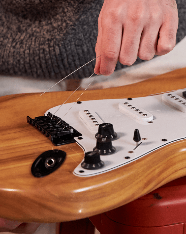 a person adjusting the strings on an electric guitar 