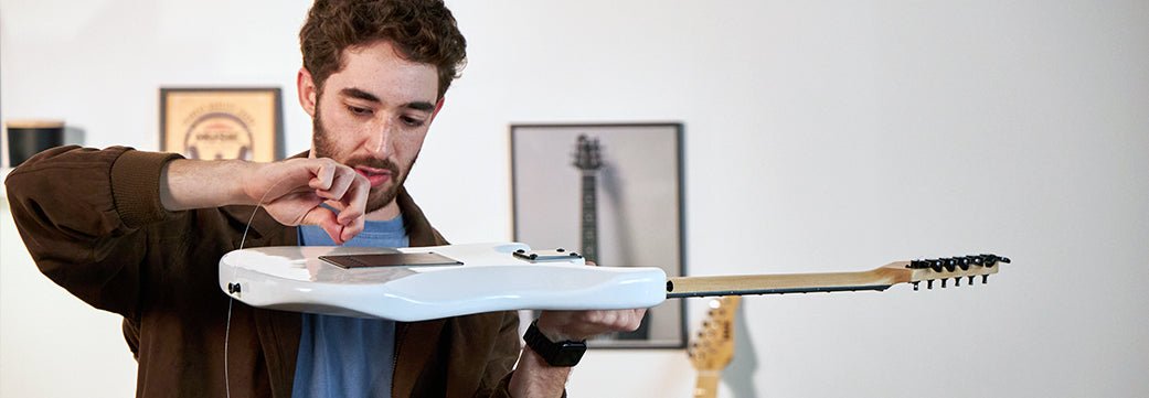 a person taking care of a white electric guitar 