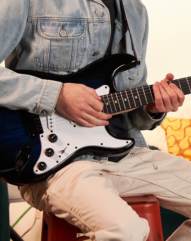 a person playing a black electric guitar