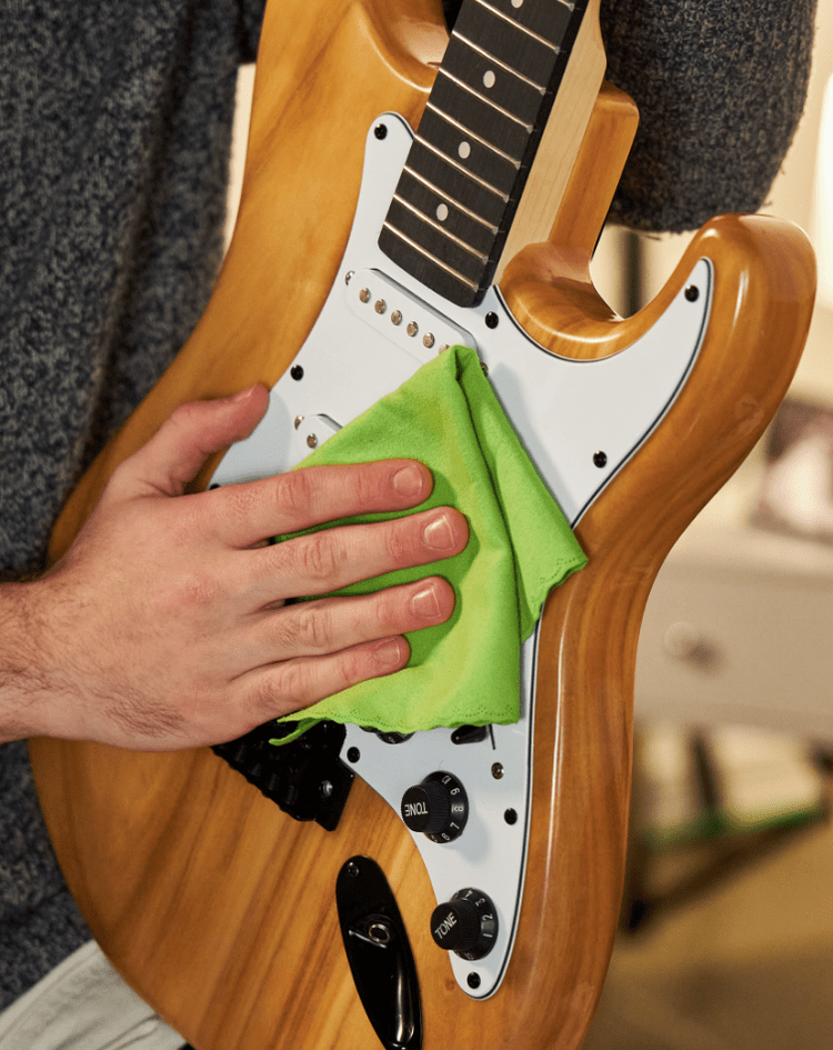 a person cleaning an electric guitar 