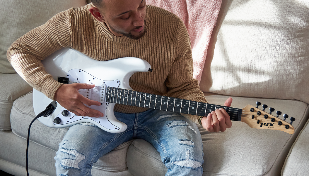 person playing a white beginner electric guitar 