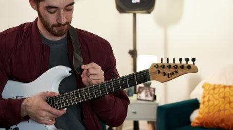 a person taking care of a white electric guitar