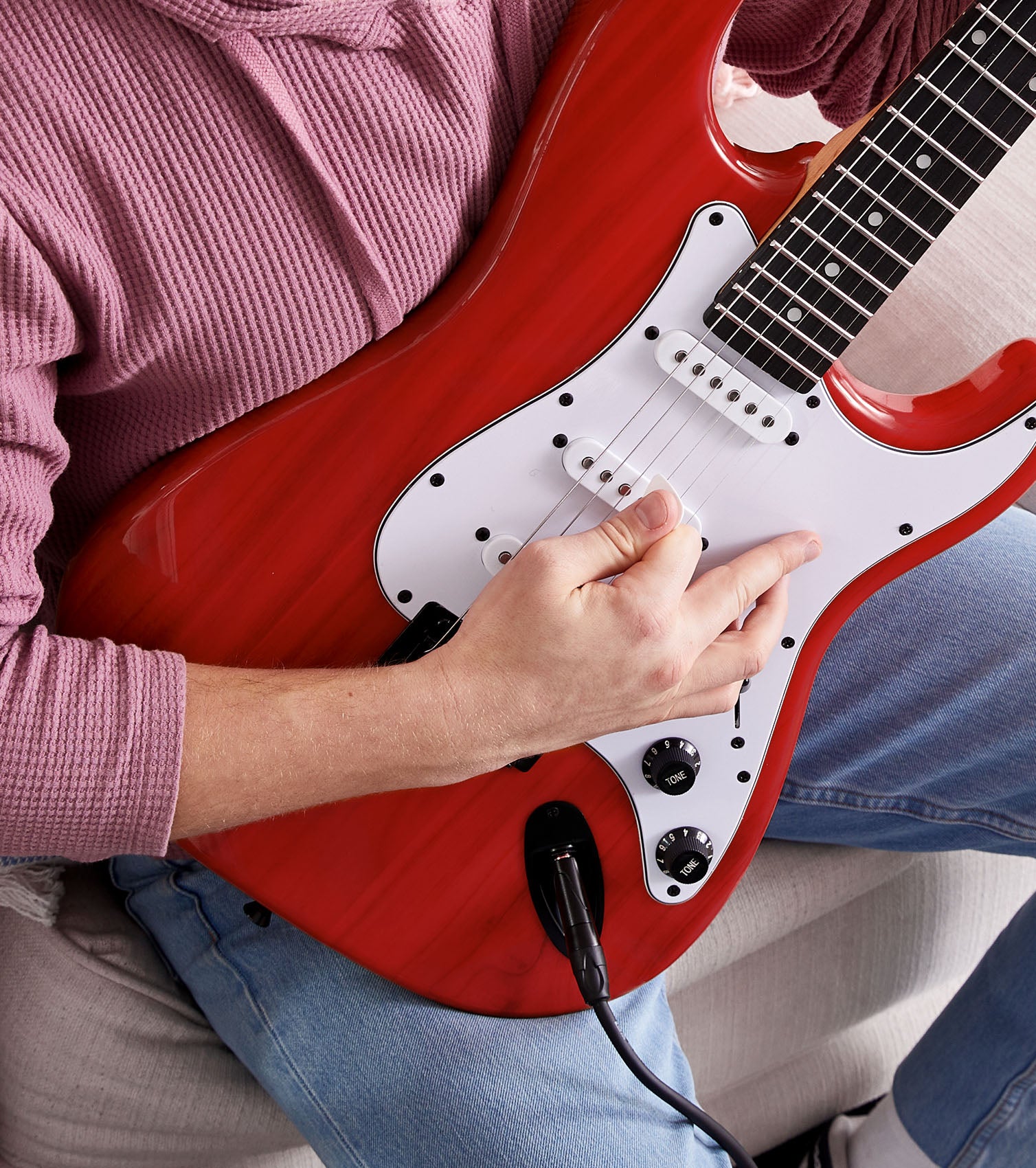 person playing Red beginner electric guitar