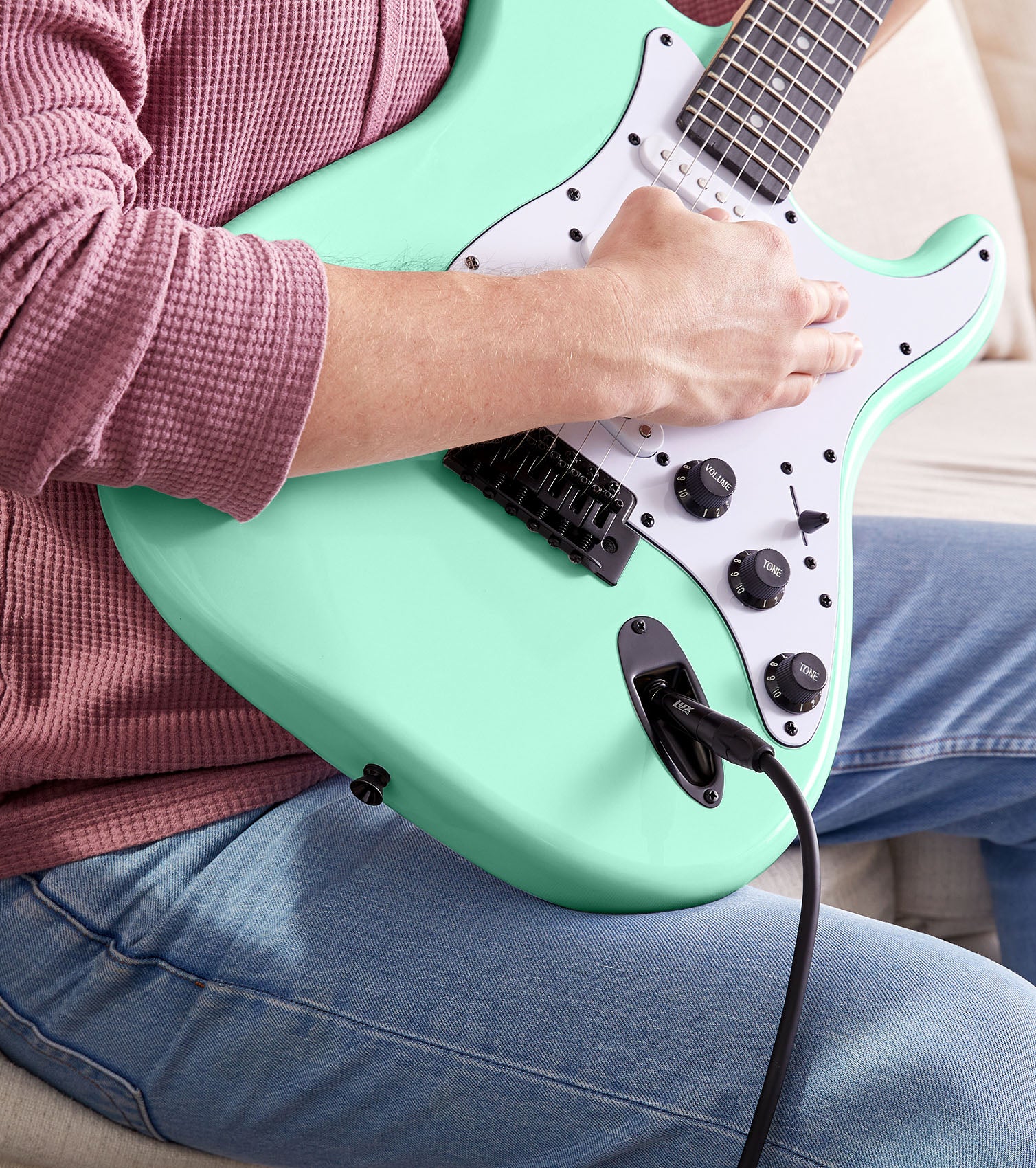 person playing Green beginner electric guitar