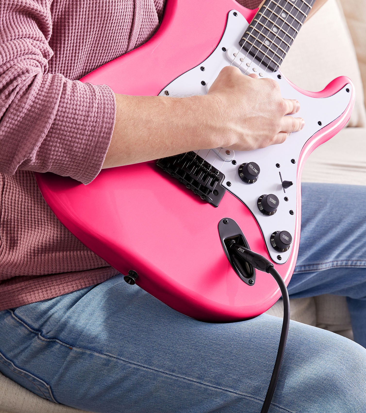 person playing Pink beginner electric guitar